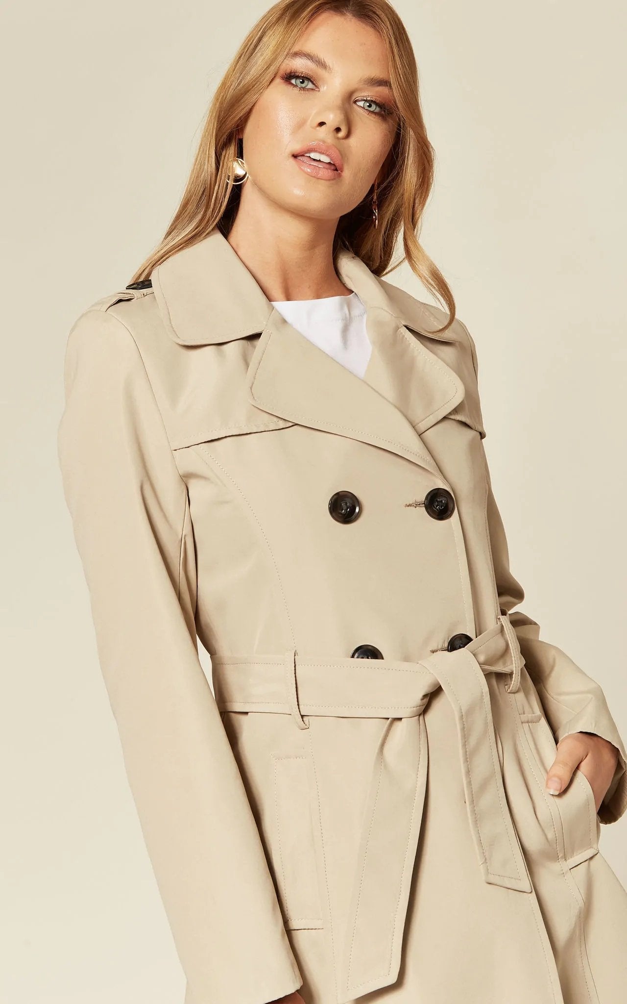Rose Eleusis military-style double-breasted trench coat in spring/summer fabric, shown in a neutral stone color.