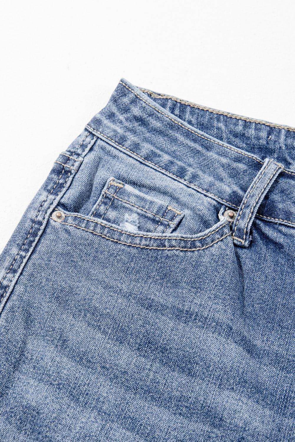Dusk blue high-rise ripped distressed hem flared jeans by Carmine Juneberry, showcasing fashionable frayed details and a fitted silhouette.