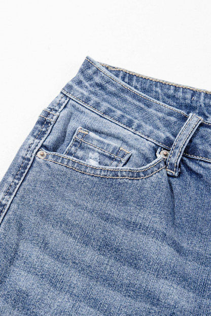 Dusk blue high-rise ripped distressed hem flared jeans by Carmine Juneberry, showcasing fashionable frayed details and a fitted silhouette.