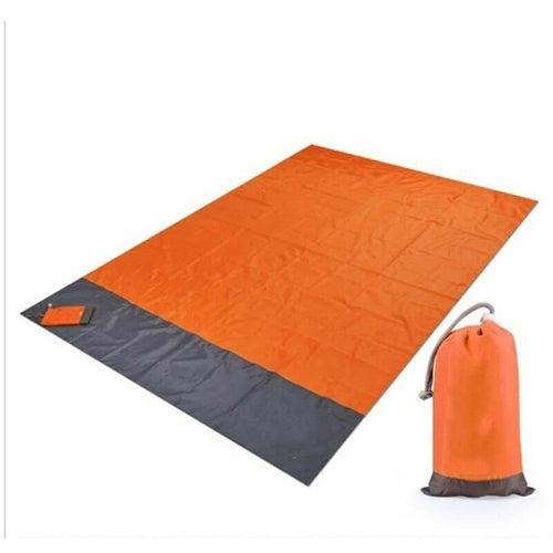 Maroon Asteria portable waterproof camping picnic mat and beach blanket spread out on sandy shore.