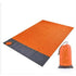 Maroon Asteria portable waterproof camping picnic mat and beach blanket spread out on sandy shore.