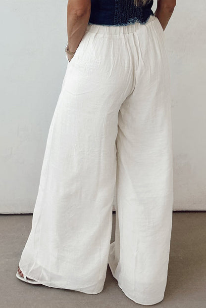 Women’s solid drop waist pleated wide-leg pants by Byzantium Bay, shown in a relaxed fit with a high waist and flowing fabric.