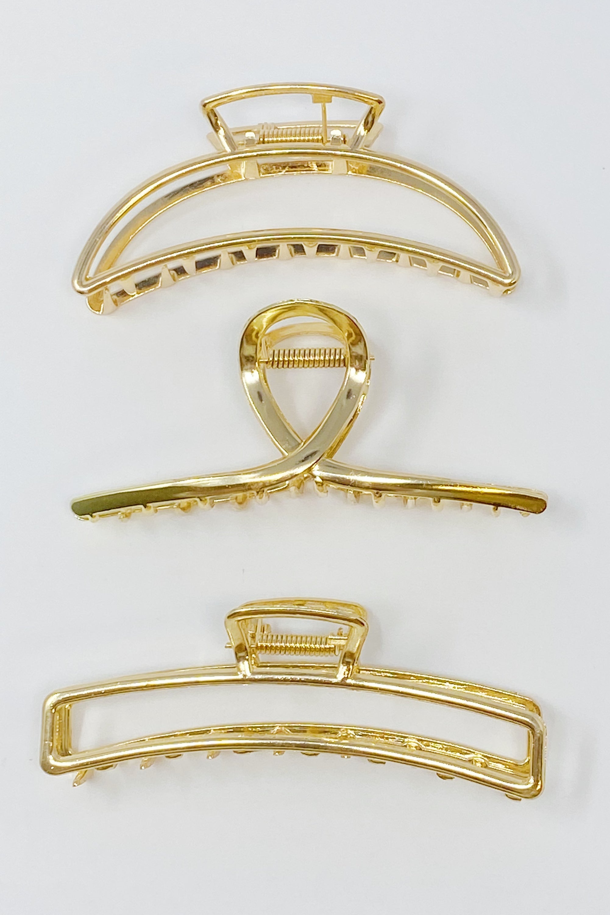 Set of three gold hair claw clips from Fuchsia Hercules, stylish jewelry accessories for securing hair.
