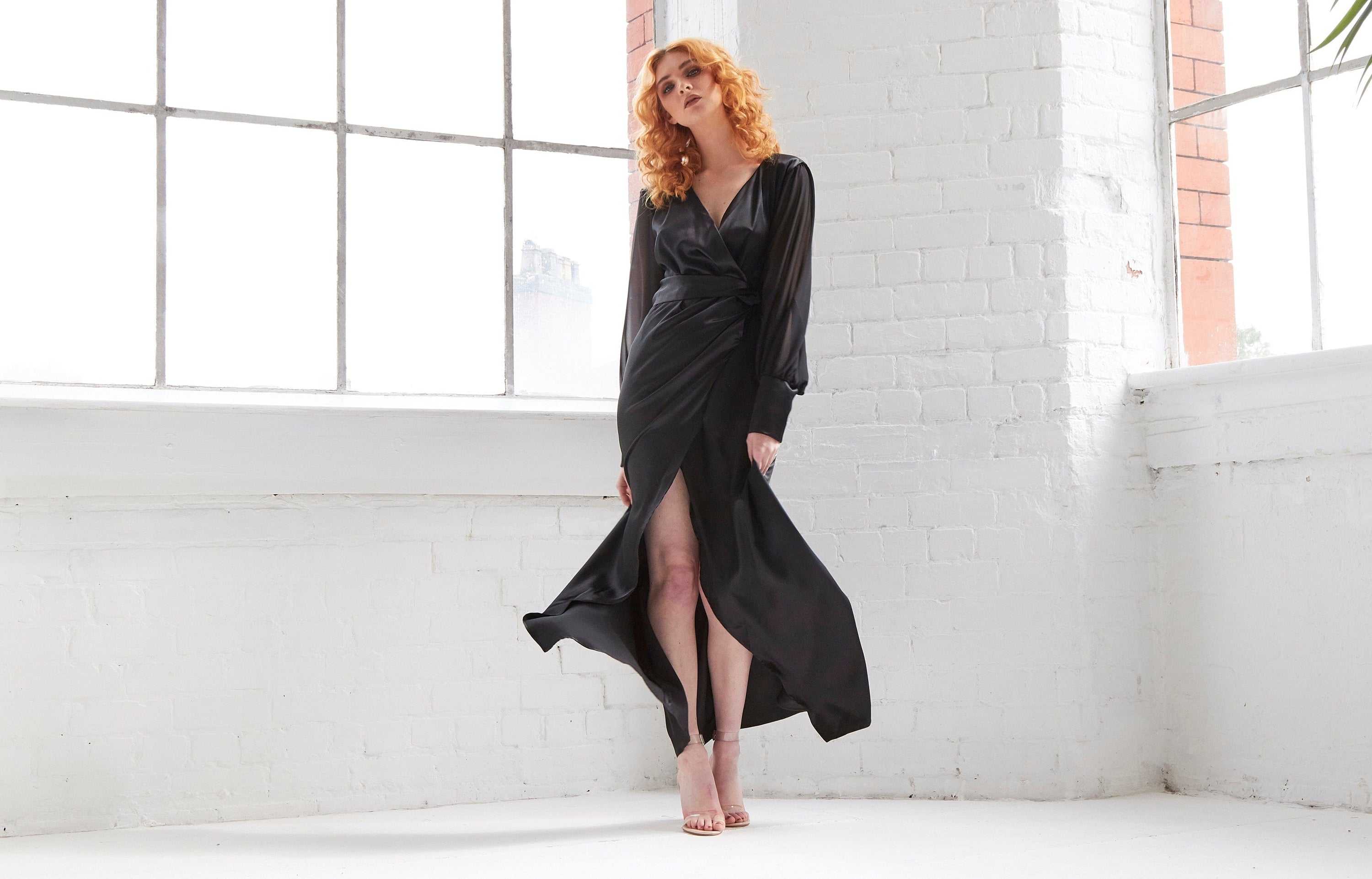 Black wrap maxi dress by Blush Athena, flowing fabric with a fitted waist and long sleeves, styled for elegant occasions.