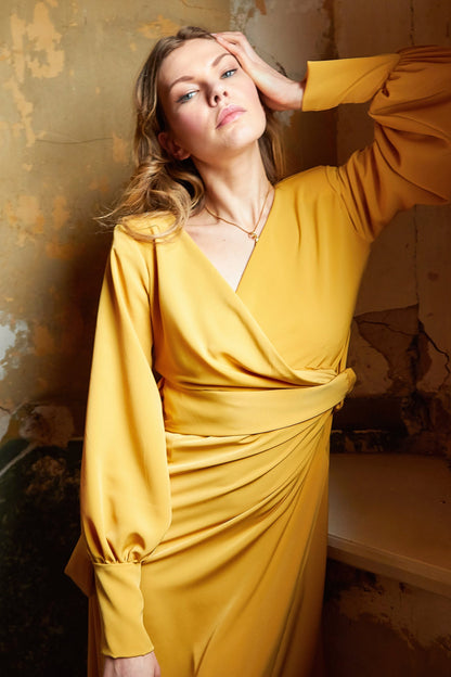 Amber V-neck wrap maxi dress with side slit by Blush Athena, featuring a mustard color and elegant drape.