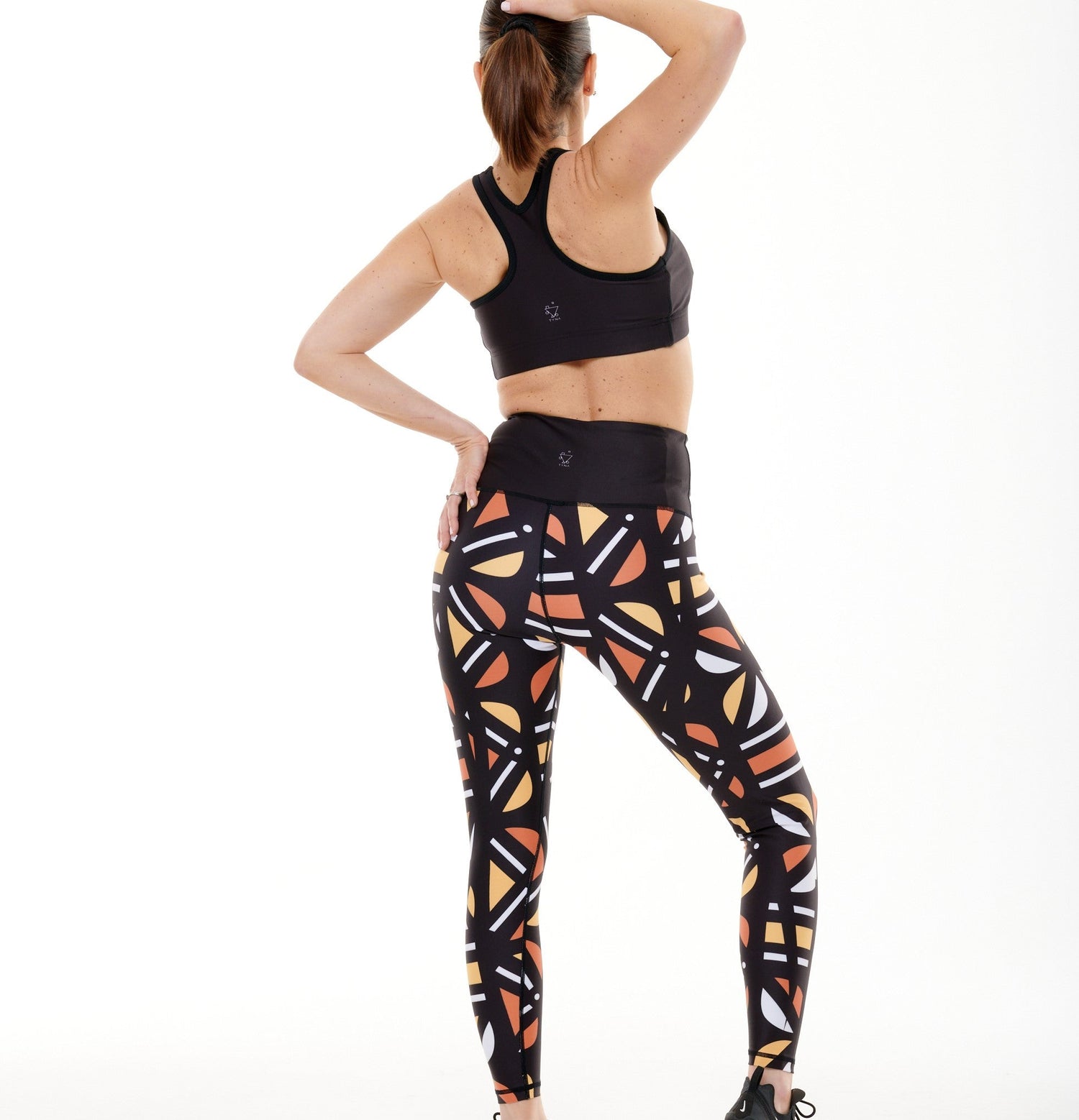 White Oliver Batiq Vibrant Leggings, activewear with colorful geometric patterns, shown from the back.