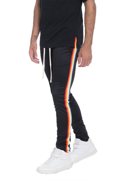 Full rainbow track pants by Lime Milo, showing vibrant multicolor design and relaxed fit, perfect for active wear.