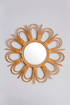 Sunburst natural rattan mirror with a floral design, featuring a round shape and intricate woven rattan frame for home decor.