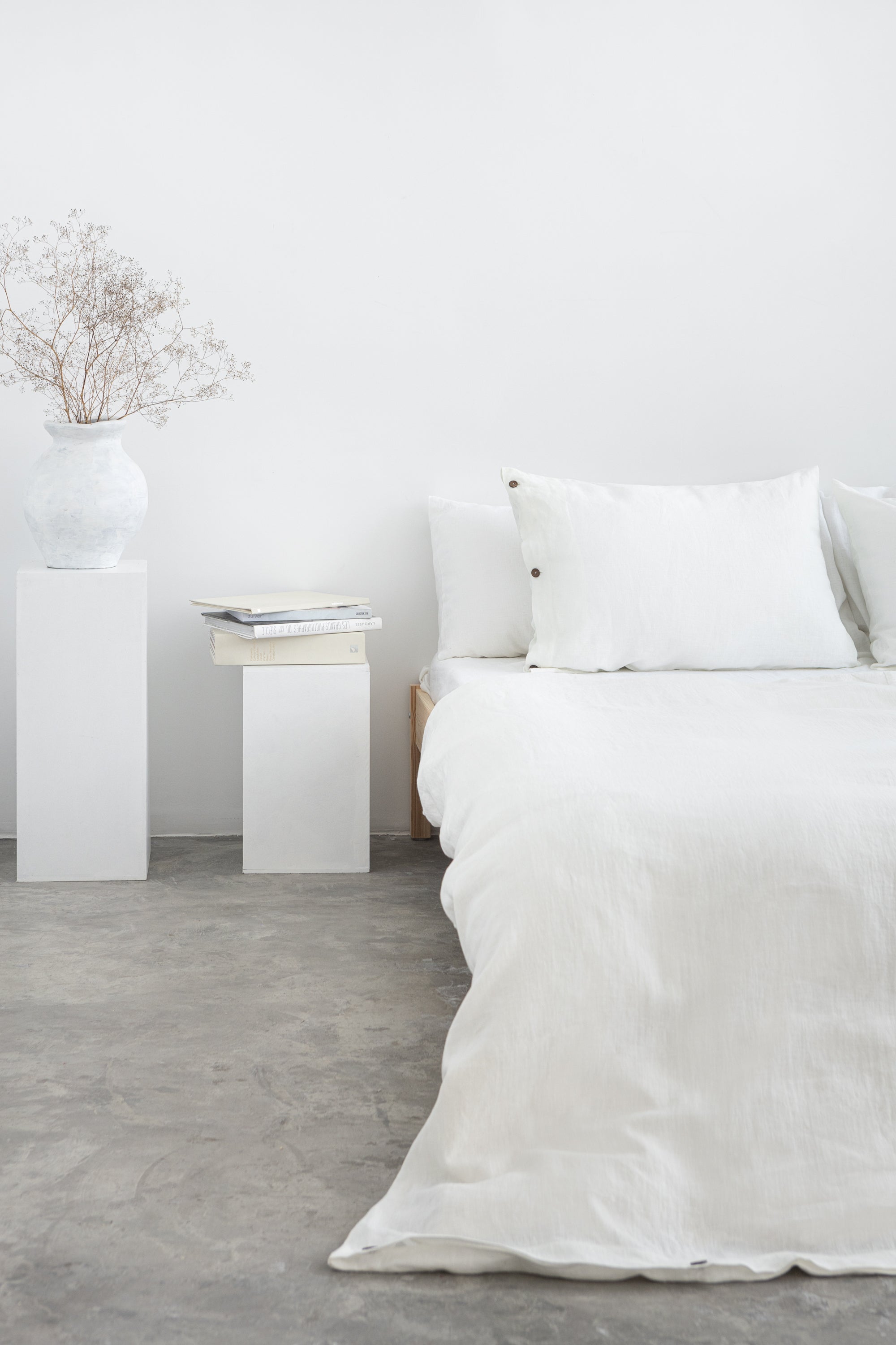 White linen bedding set with coconut button accents, stylish home decor by Magenta Sugarplum, shown on a neatly made bed.