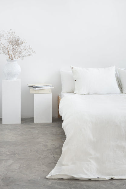 White linen bedding set with coconut button accents, stylish home decor by Magenta Sugarplum, shown on a neatly made bed.