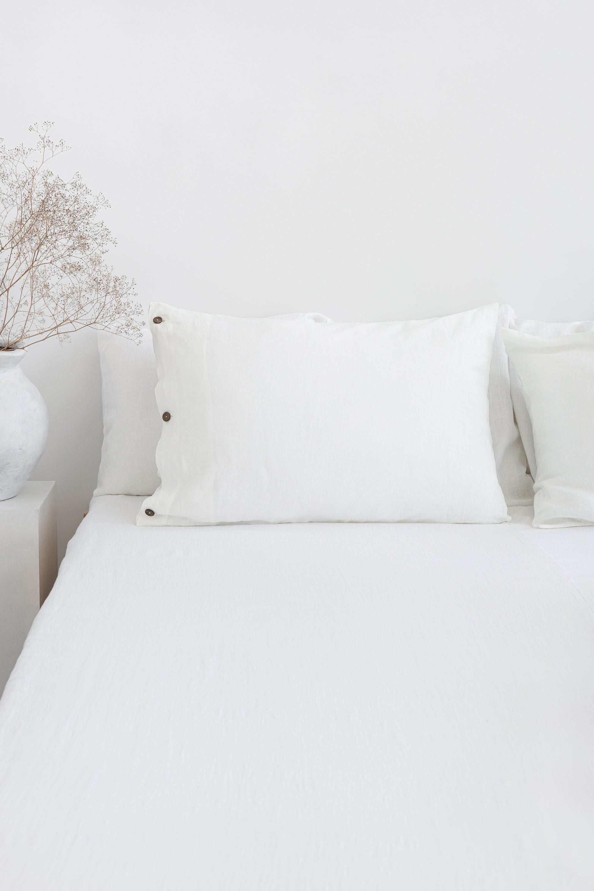 White linen bedding set with coconut button details, stylish home decor from Magenta Sugarplum.