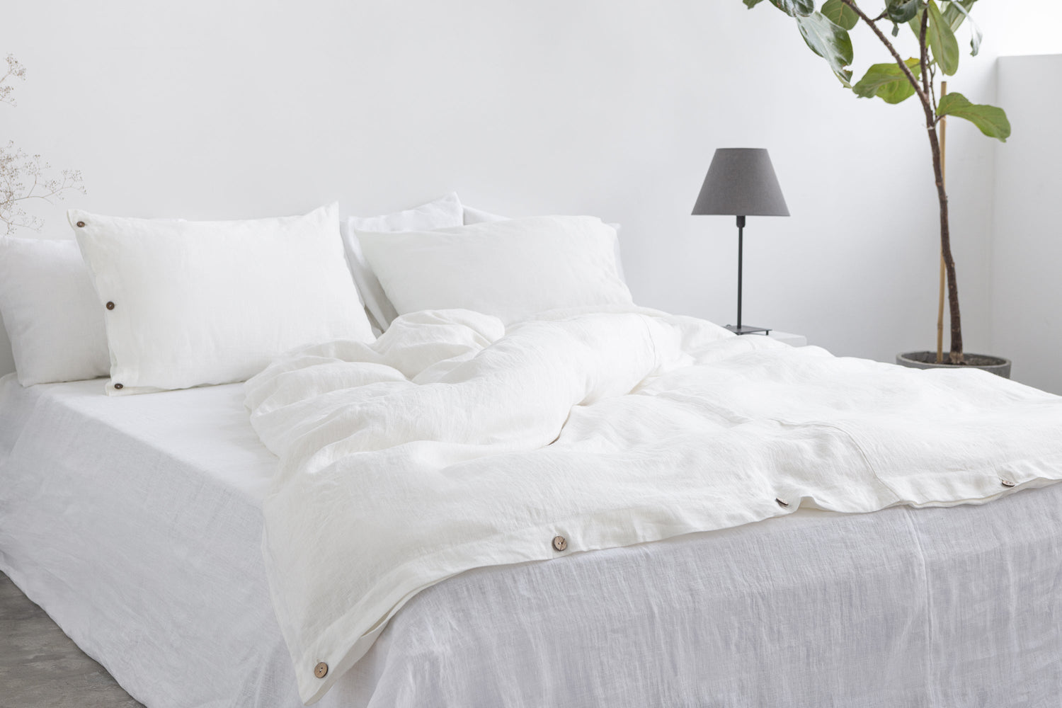 White linen bedding set with coconut button accents, showcasing a cozy, elegant home decor look by Magenta Sugarplum.