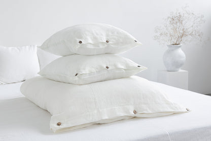 White linen bedding set with coconut button accents, stylish home decor by Magenta Sugarplum, shown on a neatly made bed.