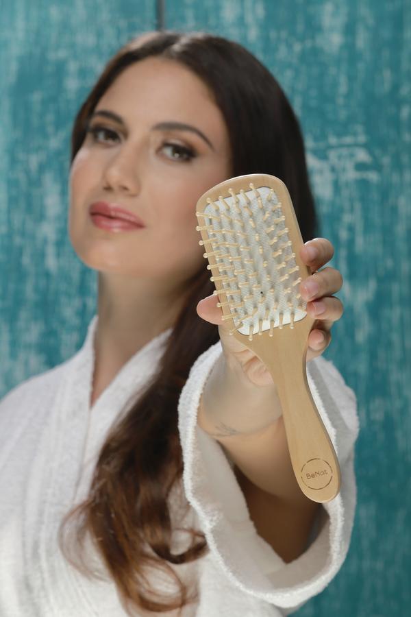 Natural wooden detangling hair brush by Jade Chrysippus, designed for gentle hair detangling in bathroom settings.