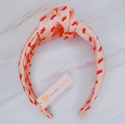 Fuchsia Hercules satin headband with cherry and bow embellishments, stylish jewelry accessory for women.