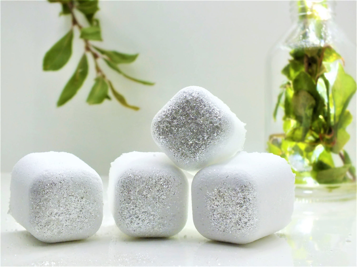 Silver Polyxena Poppy Seed bath bullets, natural and naked, displayed in a clear glass jar with fresh poppy flowers for a soothing bath experience.