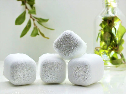 Silver Polyxena Poppy Seed bath bullets, natural and naked, displayed in a clear glass jar with fresh poppy flowers for a soothing bath experience.