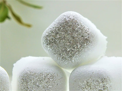 Silver Polyxena Poppy Seed bath bullets in a natural diffuser, showcasing the textured bath product with a soft, calming background.