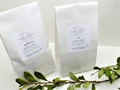 Silver Polyxena Poppy Seed bath bullets from Natural &amp; Naked, displayed in a clear diffuser bottle with floral accents.