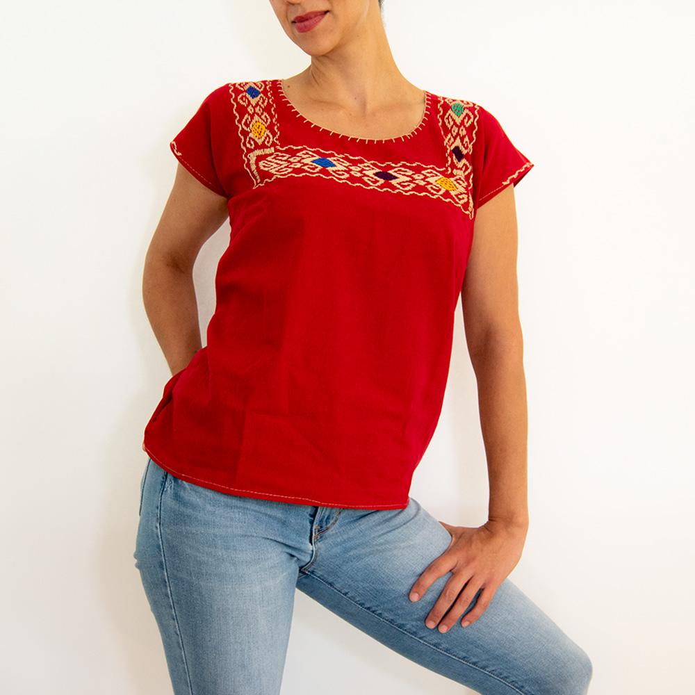Red women’s blouse huipil with colorful hand-stitched embroidery, from Violet Athena, showcasing vibrant traditional textile craftsmanship.