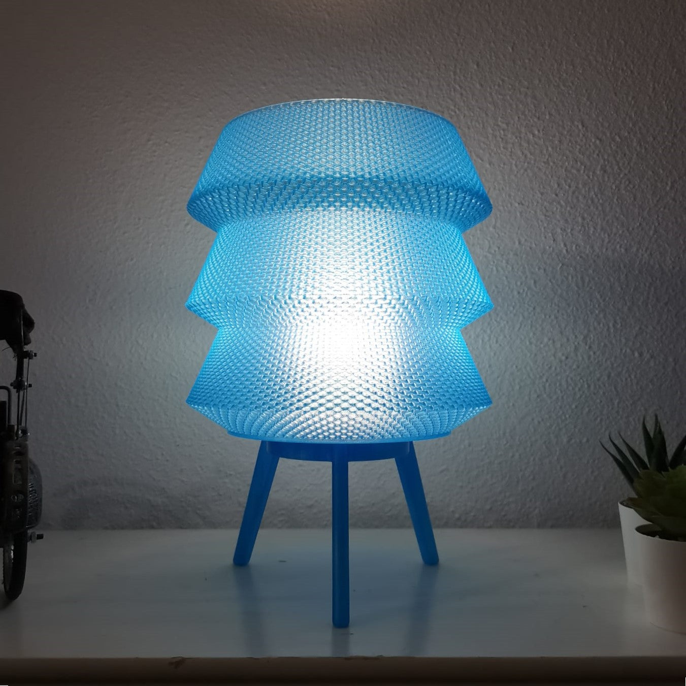 Azure Pontus Dynasty Light Table Lamp with sleek design and illuminated glass shade on a modern wooden table.