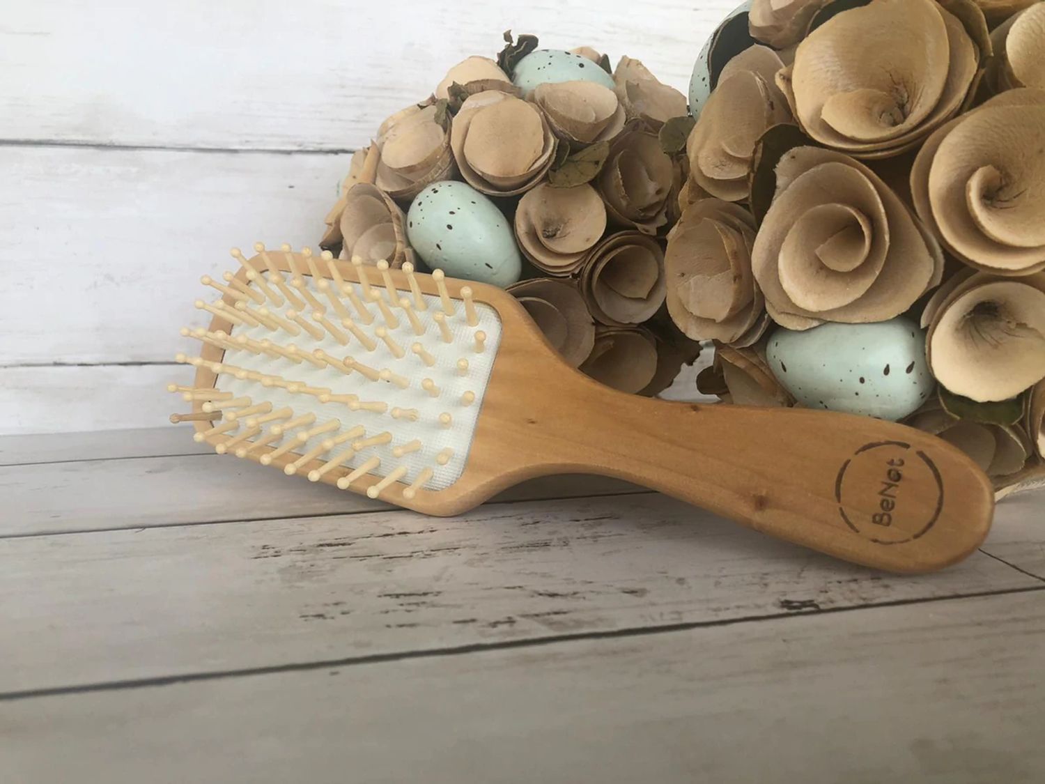 Natural wooden detangling hair brush by Jade Chrysippus for bathroom use, showing smooth wooden bristles and ergonomic handle.