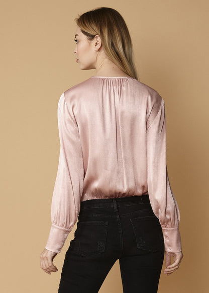 Pink tie-neck long sleeve bodysuit by Lemon Hera, featuring a fitted design and stylish neckline, on a neutral background.