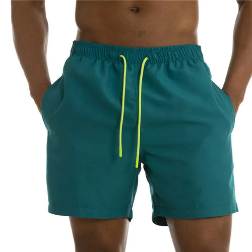 Raspberry Eurybia Sunga Beach Shorts swimwear in vibrant colors, displayed on a model at the beach.