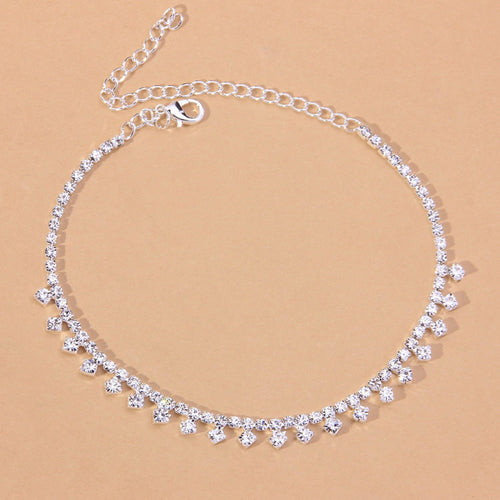 Red Iphigenia barefoot chain bracelet worn on the leg, featuring delicate jewelry design for beach accessories or gift ideas.