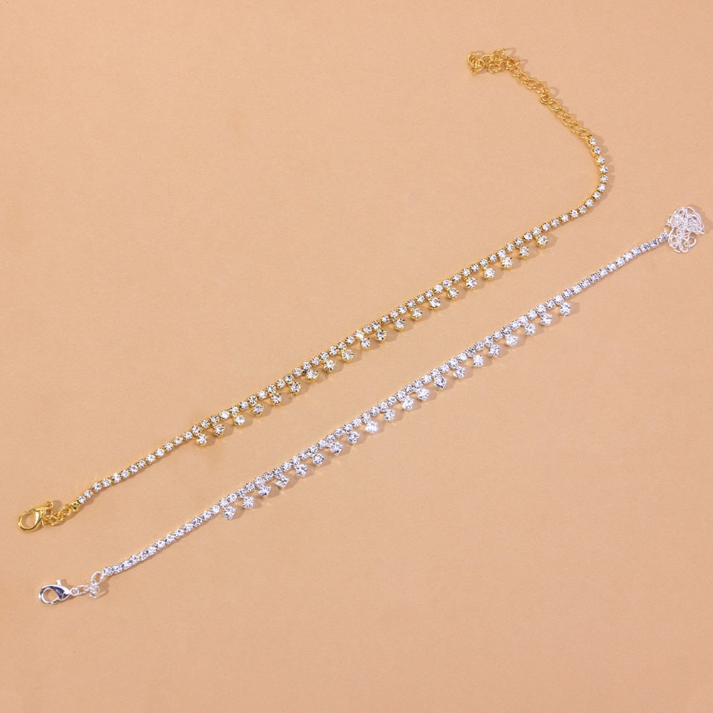 Red Iphigenia beach barefoot chain bracelet worn on the leg, showcasing delicate jewelry accessory for summer and beach wear.