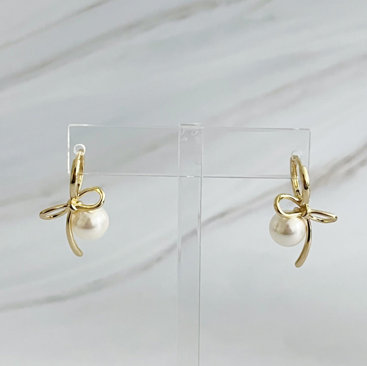 Fuchsia Hercules bowed pearl drop earrings featuring elegant jewelry design with hanging pearl accents.