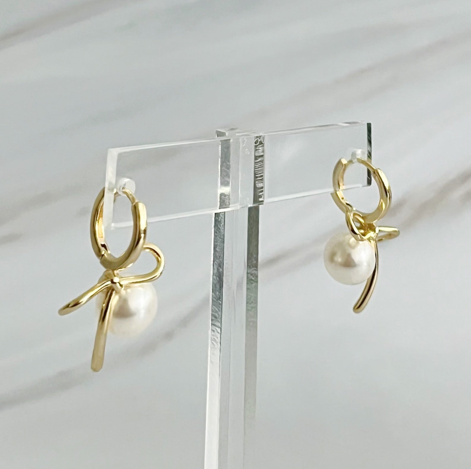 Fuchsia Hercules bowed pearl drop earrings featuring elegant teardrop-shaped pearls and a delicate jewelry design.