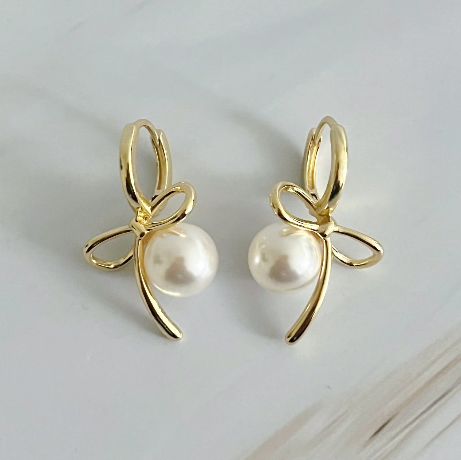 Fuchsia Hercules bowed pearl drop earrings showcasing elegant jewelry with dangling pearl accents and a polished finish.