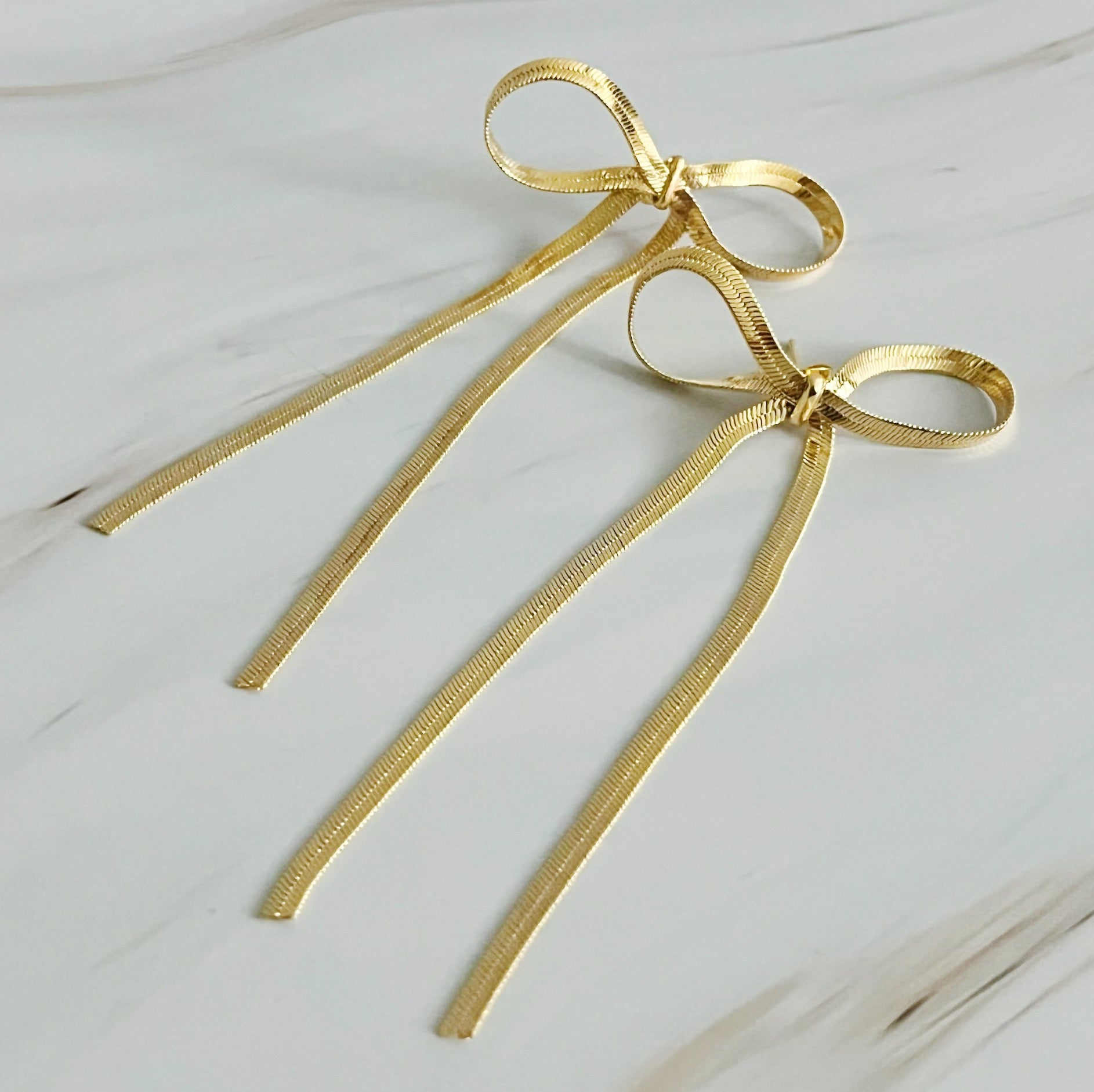 Fuchsia Hercules long drop bow earrings with elegant design, showcasing intricate bow-shaped jewelry for women.
