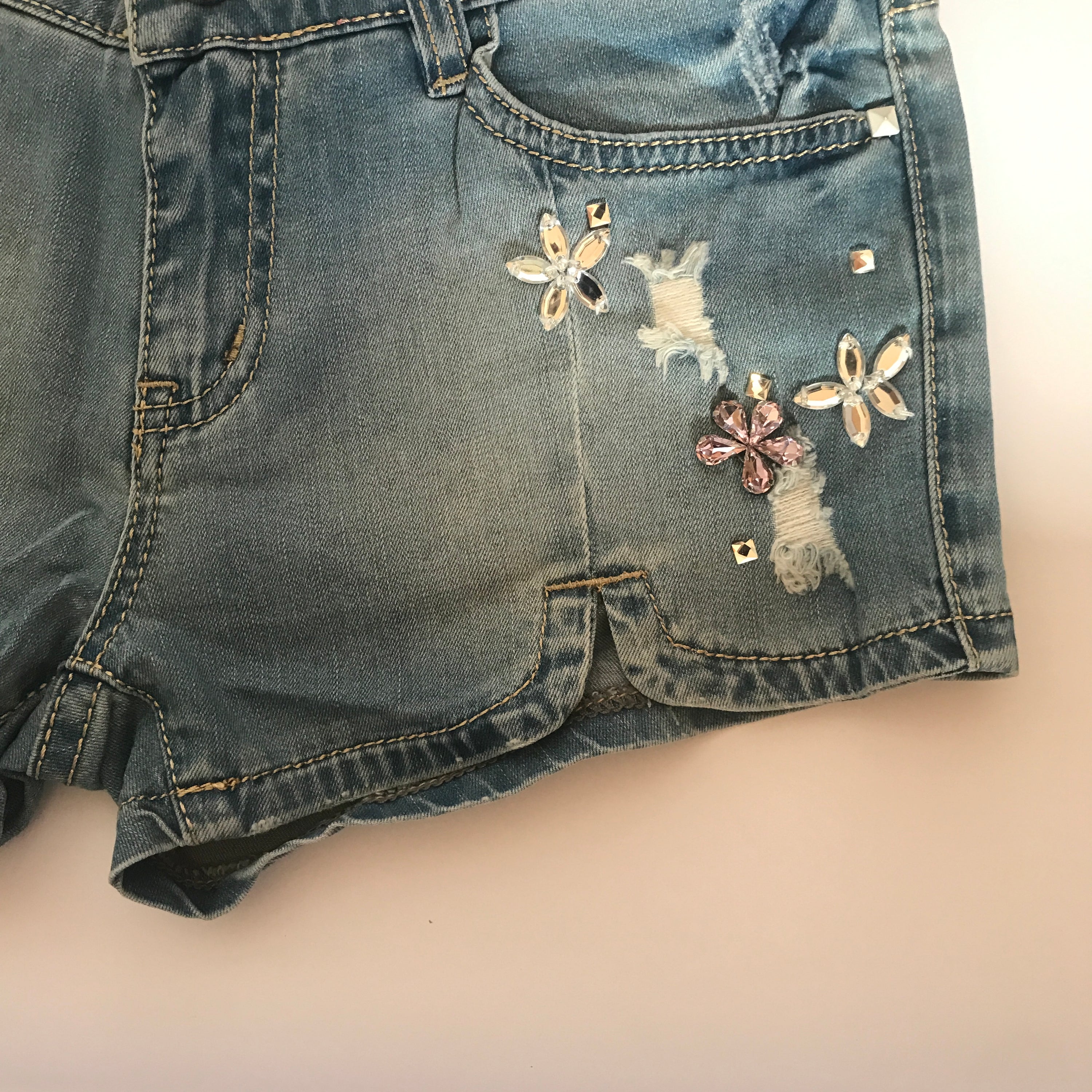 Flower rhinestones denim shorts by Blush Bella featuring floral embellishments and casual denim fabric.