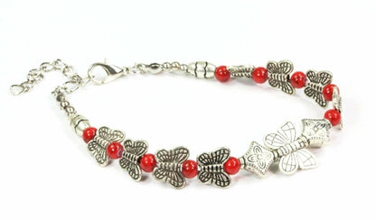 Silver Hestia bracelet with butterfly and four-leaf clover charms, featuring delicate metallic details and adjustable chain.