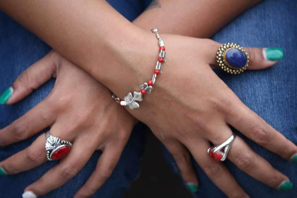 Silver Hestia bracelet featuring butterfly and four-leaf clover charms, with intricate metal detailing and adjustable chain.