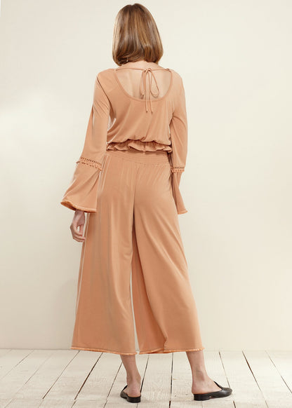 Apricot-colored smocked waist wide-leg palazzo pants by Lemon Hera, shown with flowing fabric and relaxed fit.