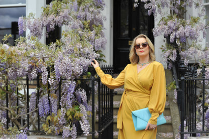 Blush Athena mustard wrap maxi dress displayed on a model, showcasing its flowing fabric and elegant design.