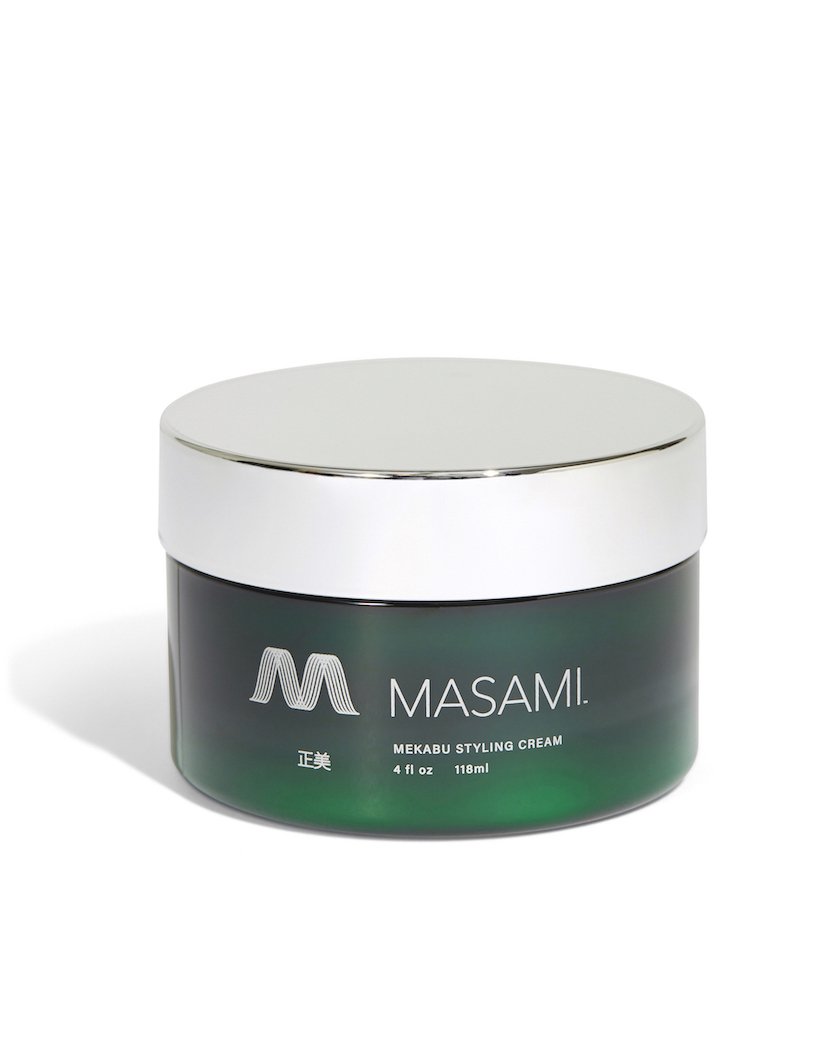 Green Saffron Mekabu Hydrating Styling Cream for hair, showing the product container with lush hair background.
