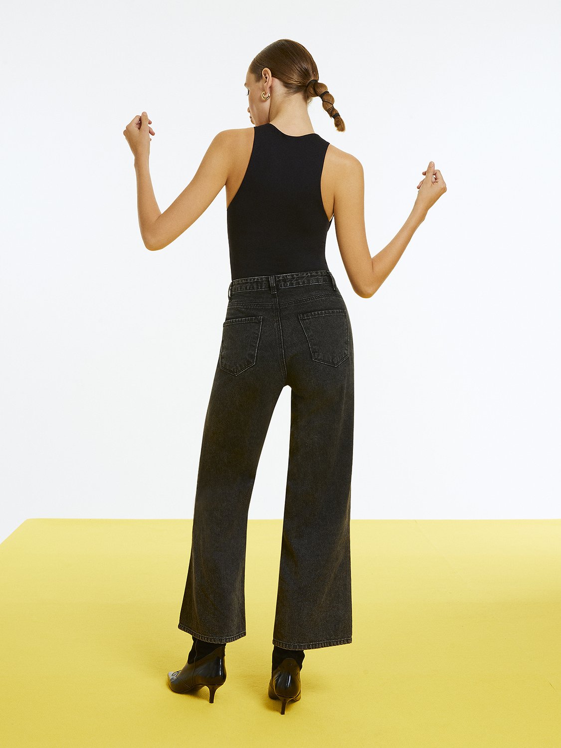 Woman wearing high-waisted ripped jeans by Bronze Aphrodite, showcasing distressed denim style and modern fit.