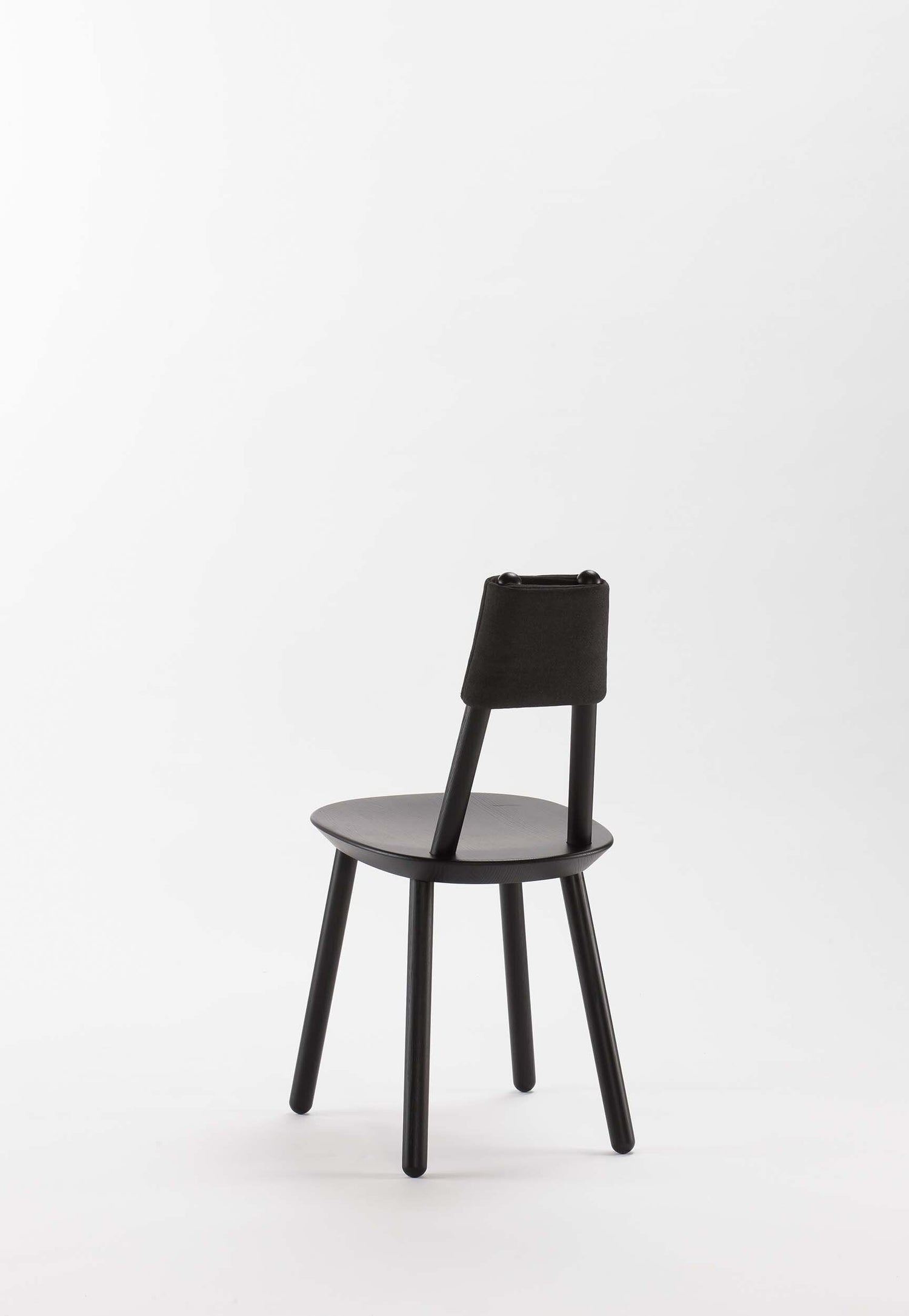 Black Naïve Dining Chair by Aquamarine Poppy, showcasing sleek modern furniture design with a curved backrest and wooden legs.