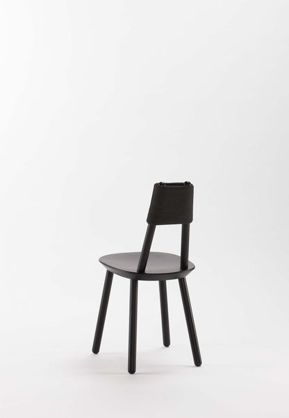 Black Naïve Dining Chair by Aquamarine Poppy, showcasing sleek modern furniture design with a curved backrest and wooden legs.