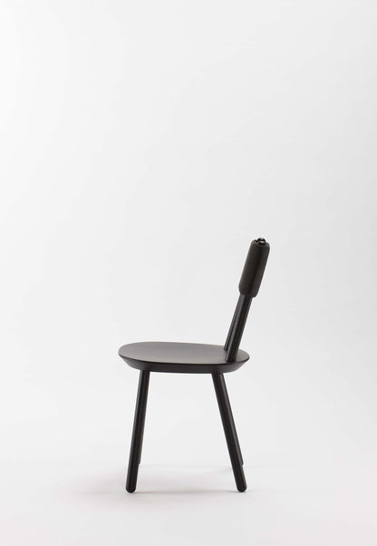 Naïve black dining chair by Aquamarine Poppy featuring a modern, sleek design with a curved backrest and wooden legs.