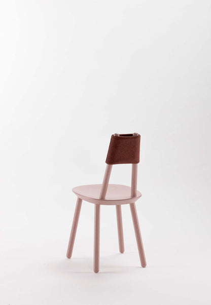 Dusty pink Naïve Dining Chair by Aquamarine Poppy with a modern design and wooden legs, shown in a cozy dining space.