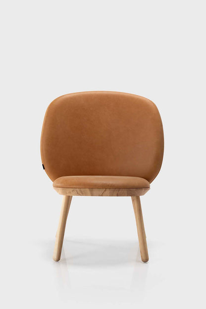 Aquamarine Poppy Naïve Low Chair in cognac leather, showcasing its modern, minimalist furniture design with wooden legs.