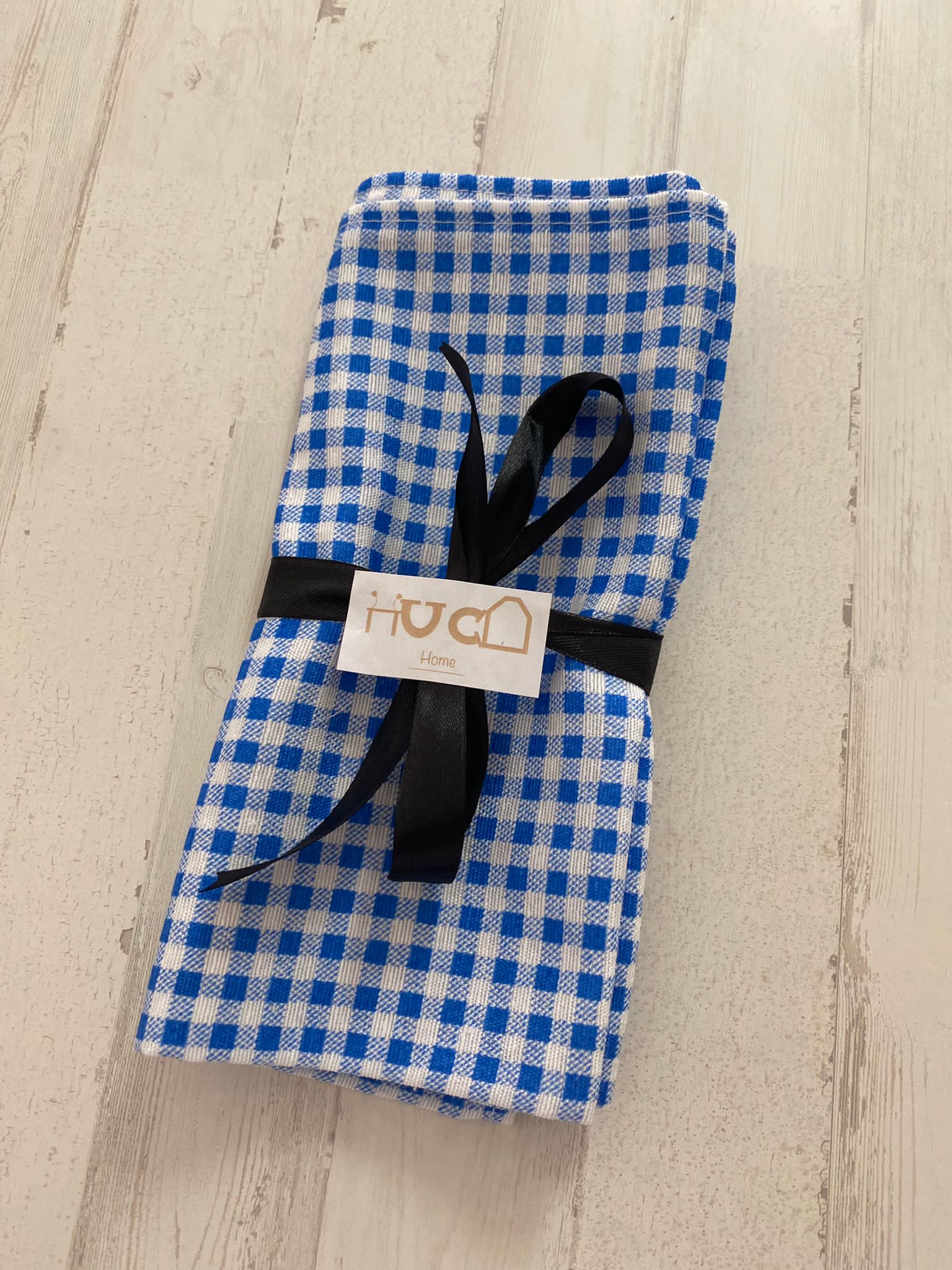 Blue Vichy patterned paper napkins by Sky Gaia for home decor, displayed in a neatly folded stack.