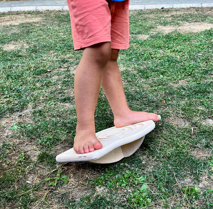 Red Oceanus Maze Wooden Balance Board resting on a flat surface, showcasing its natural wood finish and curved design for stability.
