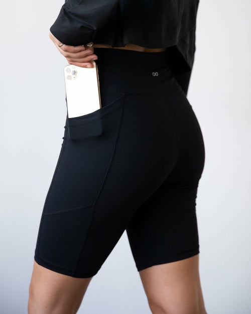Black Making Moves Pocket Biker Shorts for women by Lemon Molly, featuring a close-up of the 8.5-inch length and pocket details.