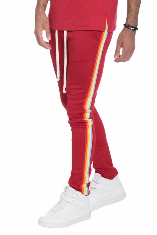 Bright rainbow track pants by Lime Milo featuring bold colorful stripes, full-length athletic pants for active wear.